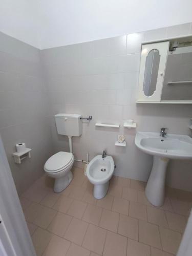a white bathroom with a toilet and a sink at Anthos Residence sul mare in Cariati