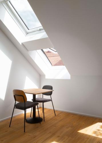 a table and chairs in a room with a skylight at Limehome Graz Trauttmansdorffgasse in Graz