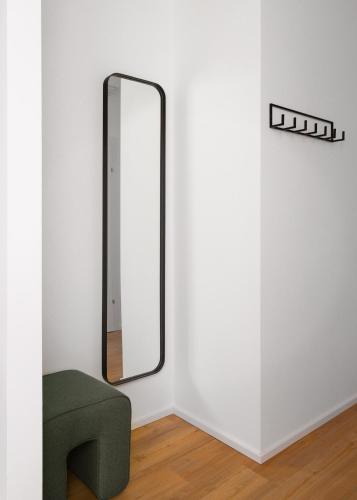 a mirror on a wall next to a green chair at Limehome Graz Trauttmansdorffgasse in Graz