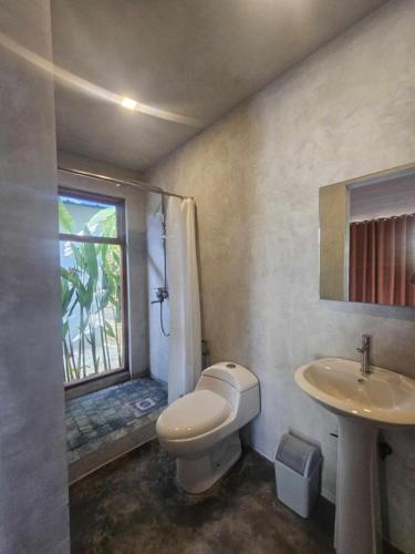 a bathroom with a toilet and a sink and a window at WADI Hut Siargao in General Luna