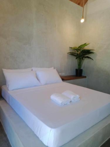 a large white bed with two towels on it at WADI Hut Siargao in General Luna