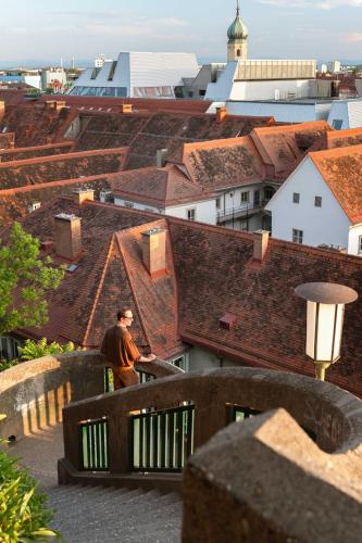 a man standing on the ledge of a roof at Limehome Graz Trauttmansdorffgasse in Graz