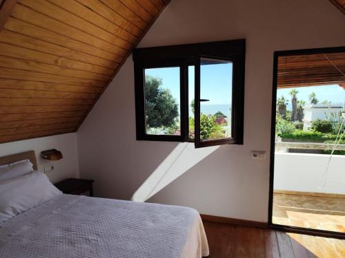 a bedroom with a bed and two windows at Casas La Pequeña Lulu in Los Caños de Meca