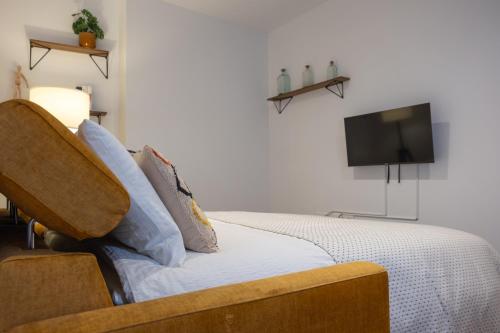 a bedroom with a bed with a tv on the wall at Apartamentos "El Aljibe" - Parking incluido in Badajoz