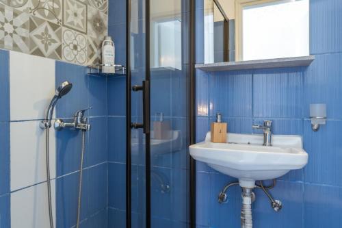 a blue bathroom with a sink and a shower at Porto Galini Kalloni in Agios Ioannis Tinos