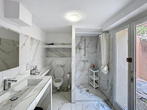 a white bathroom with a toilet and a sink at Avignon maison à côté du tram et avec jacuzzy in Avignon