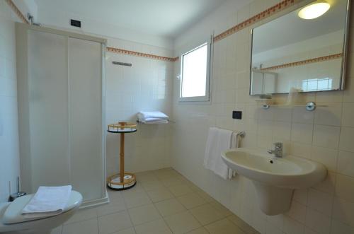 a white bathroom with a sink and a mirror at Hotel Tivoli in Lignano Sabbiadoro