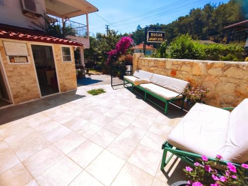 a patio with two lounge chairs and a stone wall at Bucak Apart Hotel Göcek & Beach in Göcek