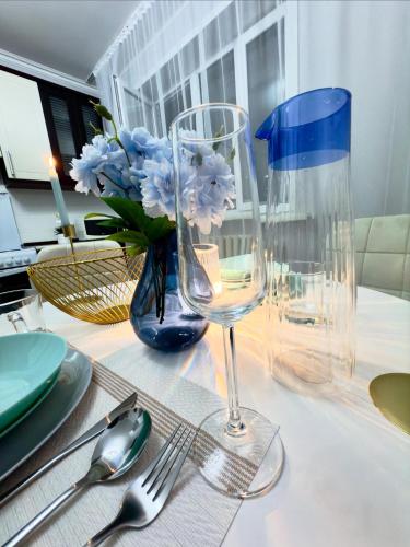 a table with a wine glass and a vase with blue flowers at ЖК ТУМАР, в самом центре города in Astana