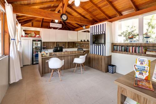 una cocina con 2 sillas blancas y una barra en Pousada Kindermann, en Florianópolis