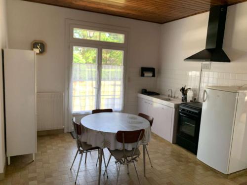 une cuisine avec une table, des chaises et un réfrigérateur dans l'établissement Roselieres de la mer Saint Hilaire de Riez, à Saint-Hilaire-de-Riez