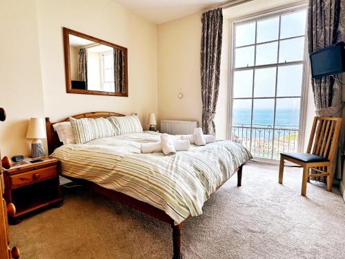 a bedroom with a bed and a large window at Harbour View in Ilfracombe