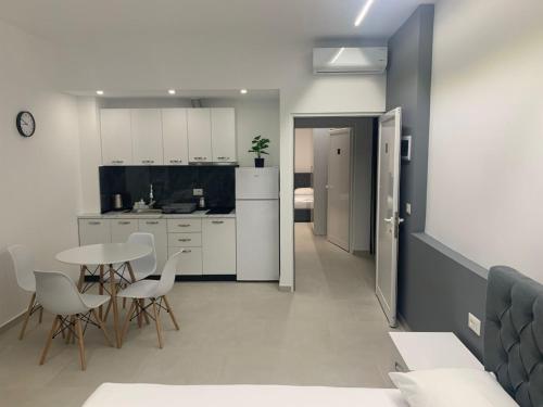 Una cocina con gabinetes blancos y una mesa y sillas. en Vila Topi, en Vlorë