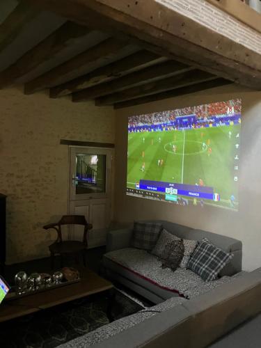 a living room with a large tv and a couch at Maison de vacances avec piscine chauffée, jacuzzi et jardin privé - proche circuit des 24h du Mans in Saint-Christophe-en-Champagne