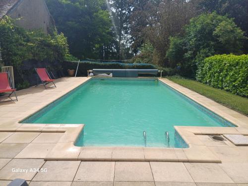 - une piscine dans une cour avec 2 chaises rouges dans l'établissement La Roulotte Authentique au pays de George Sand, à Mouhers