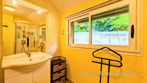 une salle de bains jaune avec lavabo et fenêtre. dans l'établissement Authentique Piscine Couverte Chauffée Vue Nature, à Guéméné-Penfao