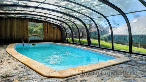 une grande piscine dans une serre avec une piscine dans l'établissement Authentique Piscine Couverte Chauffée Vue Nature, à Guéméné-Penfao
