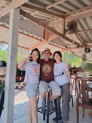 a man and two women sitting on a chair under ailion at Wandee Resort Bankrut in Ban Krut