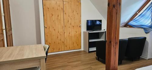 a small room with a tv and a wooden door at Éva Vendégház in Kaposvár