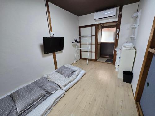 a bedroom with a bed and a flat screen tv at TSUBAME 202 staying private home in Osaka
