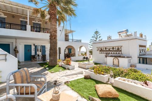 a courtyard with a palm tree and a building at Porto Galini Tinos Karya 102 in Agios Ioannis Tinos