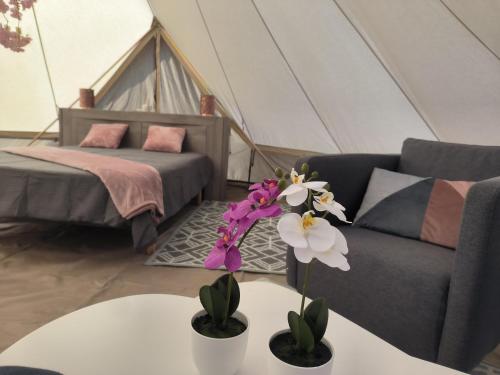 a living room with a couch and a table with flowers at lodge romantique "plein champ" et son jacuzzi privatif in Lapalisse