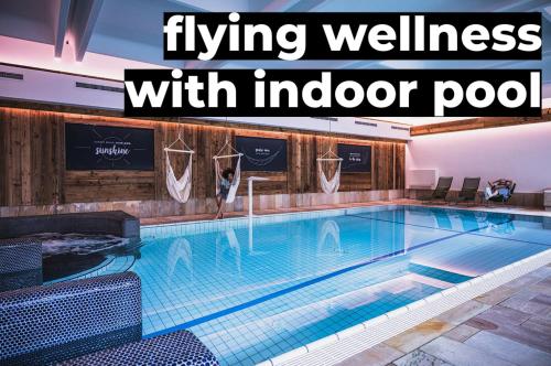 una grande piscina con la scritta living wellness con piscina coperta di Sport & Wellness Hotel Das Falkenstein - Natural Swimming Lake - Matrix GYM - Summercard inklusive - Authentic experience - Flying wellness with Pool a Kaprun
