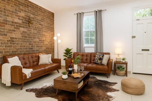 a living room with brown leather furniture and a brick wall at 3BR Glebe Retro Jungle Escape Near Darling Harbour in Sydney