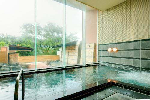 a swimming pool in a building with glass windows at 神通峡春日温泉ゆーとりあ越中 in Toyama