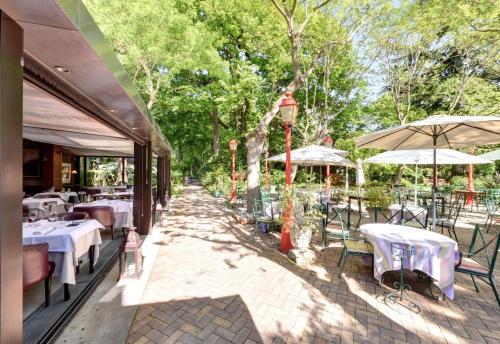 a restaurant with tables and umbrellas on a patio at CAZAUDEHORE Hôtel Restaurant Gastronomique Terrasse et Jardins in Saint-Germain-en-Laye