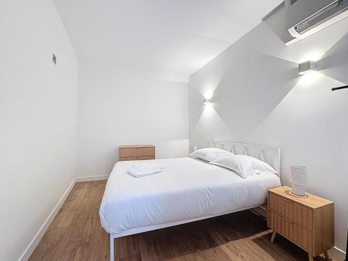 a bedroom with a white bed and a wooden floor at Mcosy2, T3, Clim, 6 Personnes, proche A75 in Coudes