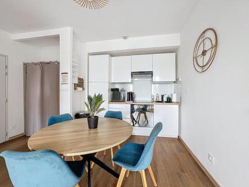 une salle à manger avec une table en bois et des chaises bleues dans l'établissement Mcosy 3, T3, 4 pers, clim, proche A75, à Coudes
