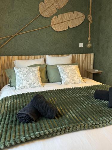 un grand lit avec une couverture verte dessus dans l'établissement Suite romantique - Escale à Bali, à Broons