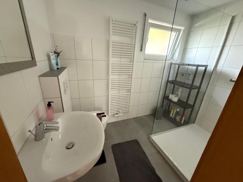 a white bathroom with a sink and a mirror at Ferienwohnung am Romberg in Lohr
