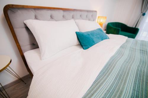 a white bed with a blue pillow on it at Cristian Point Apartment With Parking in Cristian