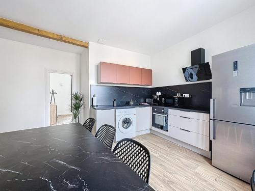 a kitchen with a table and chairs and a refrigerator at Mcosy 6, T3 premium, 6 pers, clim, terrasse, proche A75 in Coudes