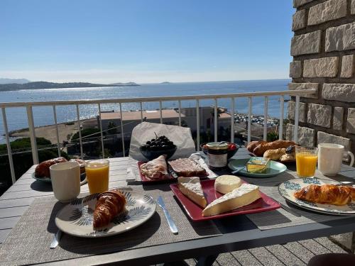 - une table avec petit-déjeuner sur un balcon donnant sur l'océan dans l'établissement Appartement T2 Mer Parking Conciergerie, à Bandol