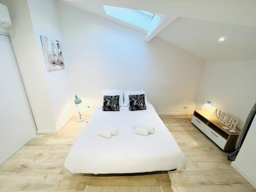 - une chambre blanche avec un grand lit blanc et 2 oreillers dans l'établissement Appartement T2 Mer Parking Conciergerie, à Bandol