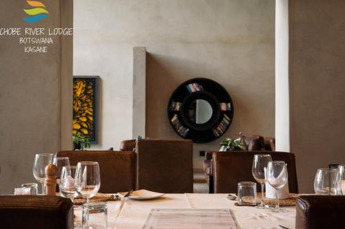 a dining room with a table with wine glasses at Chobe River Lodge in Kasane