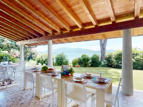 a patio with a table and chairs under a wooden roof at Villa 7 Bello by Bookinggardalake in Raffa