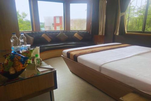 a bedroom with a bed and a couch and a table at The Kei Inn & Suites Hotel near Salt Lake in Kolkata