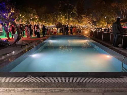a group of people standing around a pool at night at Okho Resort Kalka Panchkula in Kālka