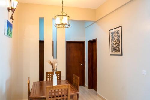 a dining room with a table and chairs and a chandelier at The Greige 3 Lakeside Condo in Entebbe in Entebbe