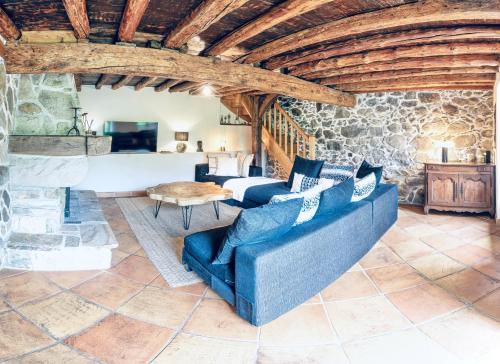 - un salon avec un canapé bleu et un mur en pierre dans l'établissement La Maison de Gourbit, à Rabat-les-Trois-Seigneurs