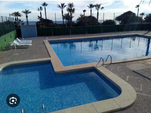 a large swimming pool with blue water at La Perla Del Mar APARTAMENT in Torrevieja