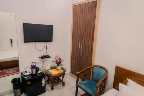 a room with a bed and a chair and a television at Peepal Tree Residency in New Delhi