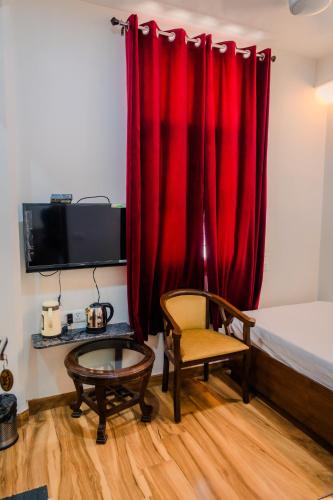 a room with a red curtain and a chair and a table at Peepal Tree Residency in New Delhi
