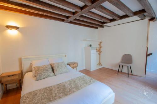 une chambre avec un lit blanc et une chaise dans l'établissement Le Penseur - Terrasse et 1 chambre - 38m2, à Orléans