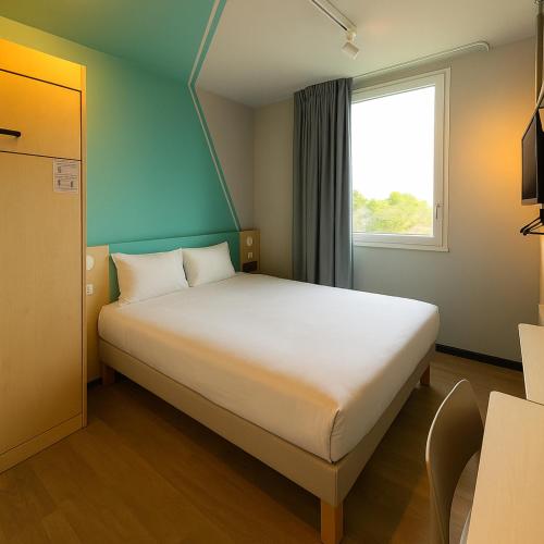 une chambre avec un grand lit avec une fenêtre dans l'établissement ibis budget Auxerre Nord, à Auxerre