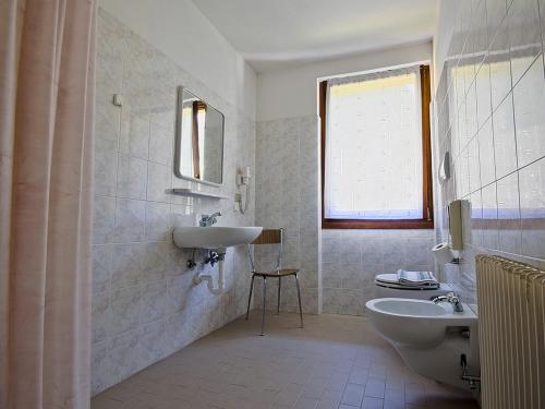 La salle de bains blanche est pourvue d'un lavabo et de toilettes. dans l'établissement Albergo Alpino da Tullio, à Avio